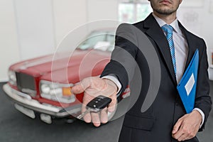 Salesman is selling a new car and passing keys