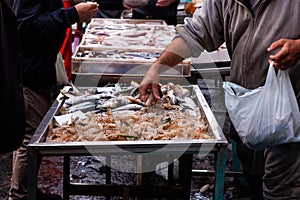 Salesman selling sea cicadas in the street fish market, Catania