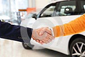 Salesman shaking hands with client in car dealership