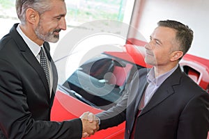 Salesman shaking hands with client after selling him car