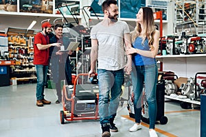 Salesman is showing couple of clients new generator in power tools store.