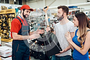 Salesman is showing couple of clients new showel in power tools store.