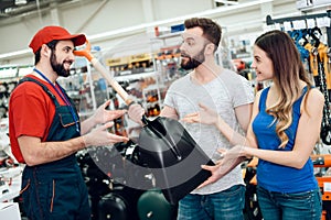 Salesman is showing couple of clients new showel in power tools store.