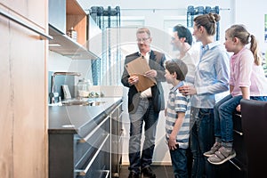 Salesman showing family the features of a new kitchen