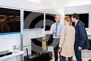 Salesman Showing Flat Screen Television To Couple In Store