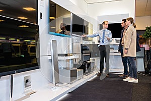 Salesman Showing Flat Screen Tv To Couple In Store