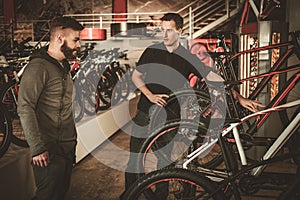 Salesman showing a new bicycle to interested customer in bike shop.