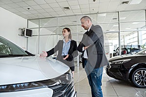 salesman showing a new modern car to the happy caucasian female client
