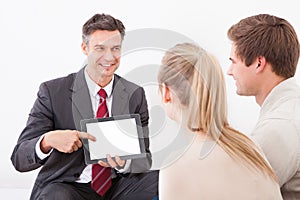 Salesman showing tablet pc to couple