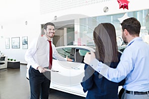 Salesman Showing White Luxury Car To Customers