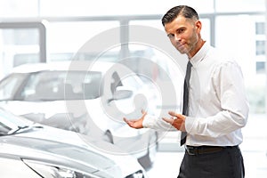 Salesman Standing at the Car Showroom and Showing New Cars