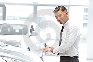 Salesman Standing at the Car Showroom and Showing New Cars