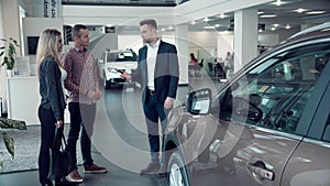 Salesman Talking to Couple inside Car Dealership