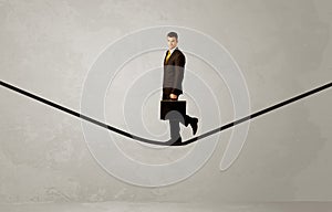 Salesman walking on rope in grey space