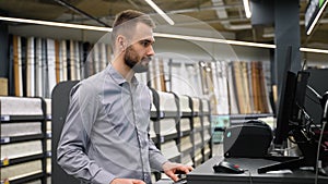 Salesman in a wall covering store checking wallpaper on computer