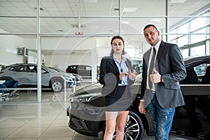salesperson in car dealership buyer show thumbs up as sign of satisfaction with purchase car