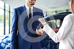 Salesperson giving car keys to man in auto dealership