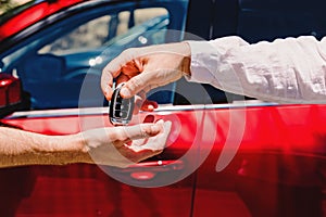 Salesperson giving car keys to the new owner