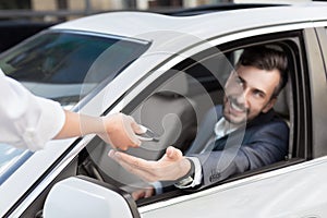 Salesperson giving keys to new car owner at dealership