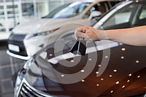 Salesperson holding keys to a new car. Modern and prestigious vehicles