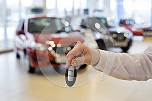 Salesperson holding keys to a new car. Modern and prestigious vehicles.