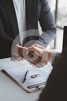 The salesperson of the housing estate in the project and the customer shake hands after successfully signing the contract. Concept