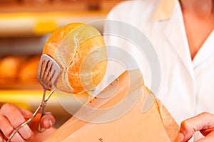 Salesperson is packing bread in bakery