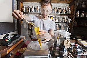 Salesperson scooping ingredient into paper bag at tea store