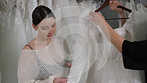 A saleswoman helps a young woman choose a wonderful wedding dress.