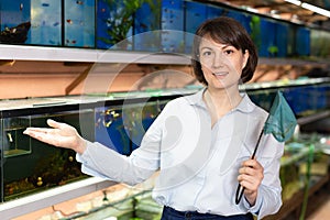 Saleswoman near aquariums with fish