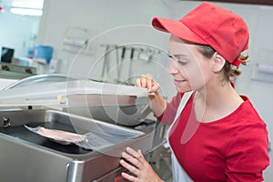 Saleswoman working with sliced meat at supermarket