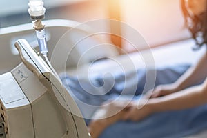 Saline intravenous IV drip for medical treatment and nursing patient in hospital with blurred family caregiver or nurse