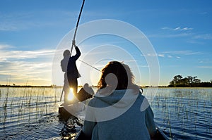 Saling in the Okavango delta at sunset, Botswana photo