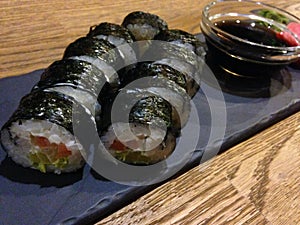 Salmon Avocado Sushi Roll on Black Tray.