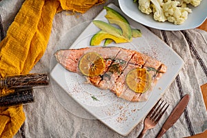 Salmon baked with avocado eneldo and lemon on white plate from top photo