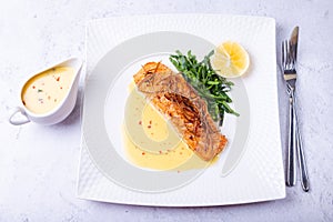 Salmon with beurre blanc sauce, spinach and lemon. Garnished with leeks. Traditional French dish. Close-up photo