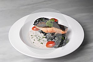 Salmon and Black pasta with tomatoes and parsley in white plate on table restaurant