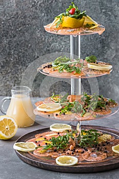 Salmon carpaccio with lemon and rocket on a cake stand, italian starter, antipasti