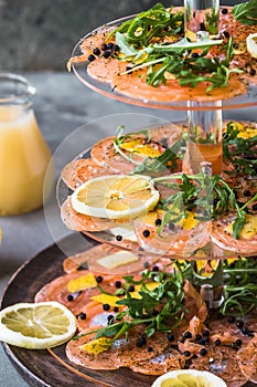 Salmon carpaccio with lemon and rocket on a cake stand, italian starter, antipasti