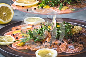 Salmon carpaccio with lemon and rocket on a cake stand, italian starter, antipasti