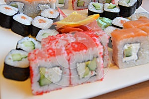 Salmon and caviar rolls served on a plate. sushi or rolls are held with chopsticks. with soy sauce, ginger and wasabi