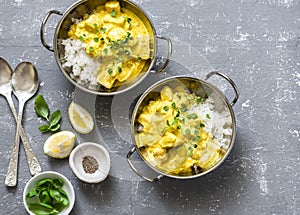 Salmon curry and rice in curry dishes on grey background, top view. Indian cusine style.