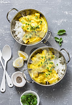 Salmon curry and rice in curry dishes on grey background, top view. Indian cusine style photo