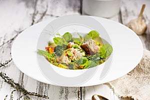 Salmon cutlet with fish broth and vegetables. Appetizing fish meatballs. Served on a white plate. Wooden white background