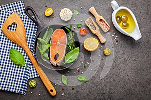 Salmon filet in old cast iron skille on dark stone background. Ingredients for making steak concept with copy space . Various