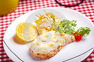 Salmon fillet served with risotto, arugula salad and lemon on white plate