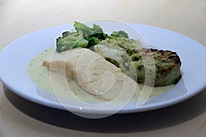 Salmon Fillet with vegetable medallions, mixed vegetable, green broccoli, lemon and dill sauce in the white dish.