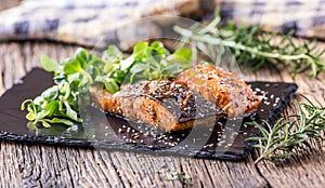 Salmon fillets. Grilled salmon, sesame seeds herb decorationon on vintage pan or black slate board.