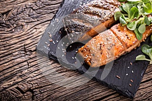 Salmon fillets. Grilled salmon, sesame seeds herb decorationon on vintage pan or black slate board.