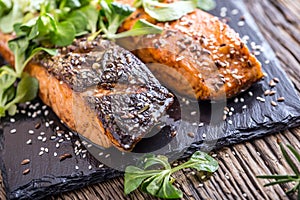 Salmon fillets. Grilled salmon, sesame seeds herb decorationon on vintage pan or black slate board.